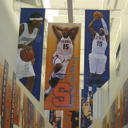 Indoor banners depicting basketball players at Syracuse University.
